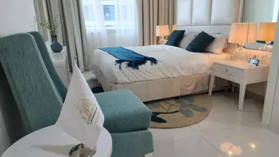 a bedroom with a bed and a chair and a couch at Damac Maison Mall Street - Downtown by Golden Casa in Dubai
