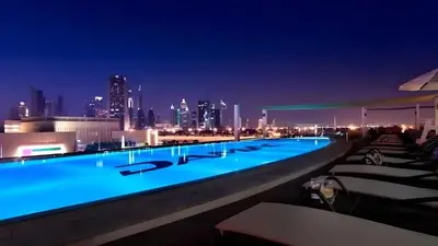a swimming pool with a city skyline at night at Damac Maison Mall Street - Downtown by Golden Casa in Dubai