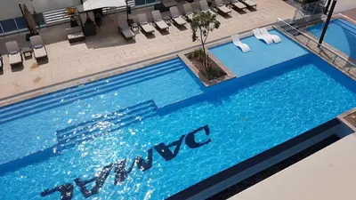 a large blue swimming pool with chairs in a building at Damac Maison Mall Street - Downtown by Golden Casa in Dubai