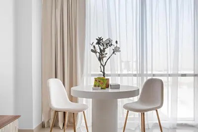 a white table with two chairs and a vase with flowers at Silkhaus Elegant Studio Near Silicon Central Mall in Dubai