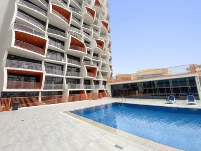 a building with a swimming pool in front of a building at Silkhaus Luxury Studio Near Silicon Shopping Mall in Dubai