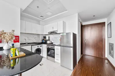 a kitchen with white appliances and a black counter top at Silkhaus Luxury Studio Near Silicon Shopping Mall in Dubai