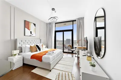 a white bedroom with a bed and a mirror at Silkhaus Modern Studio near Silicon Shopping Mall in Dubai