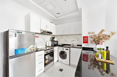 a kitchen with a refrigerator and a washer and dryer at Silkhaus Modern Studio near Silicon Shopping Mall in Dubai