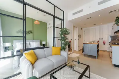 a living room with a couch and a kitchen at Cozy One Bedroom Near Dubai Hills Mall in Dubai