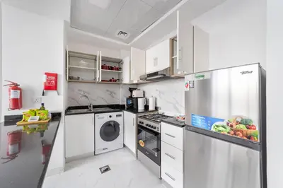 a kitchen with a refrigerator and a washing machine at Silkhaus Chic Studio Near Silicon Oasis Shopping Mall in Dubai