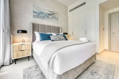 a bedroom with a large white bed with blue pillows at Cozy 1BR Haven in The Cove, Dubai Creek Harbour in Dubai