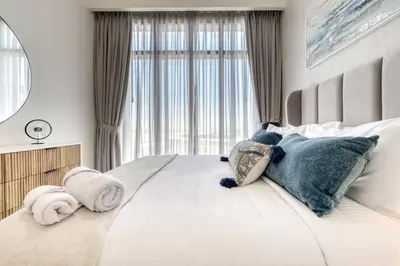 a bedroom with a large bed with pillows and a window at Cozy 1BR Haven in The Cove, Dubai Creek Harbour in Dubai
