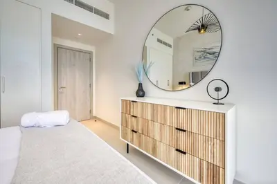 a bedroom with a large mirror above a dresser at Cozy 1BR Haven in The Cove, Dubai Creek Harbour in Dubai