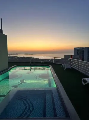 a swimming pool on top of a building with the sunset at Fantastic Apartment near Metro and jbr beach in Dubai