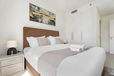 a white bedroom with a large bed with white pillows at Luxurious 2 BR in Downtown Dubai in Dubai