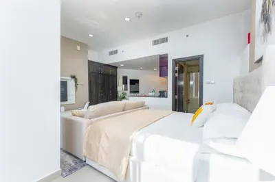 a white bedroom with a bed and a couch at Cayan Tower Dubai Marina - By Home Of Choice in Dubai