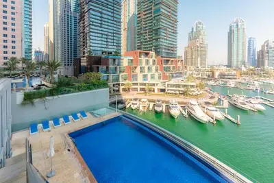 a swimming pool on a building with boats in the water at Cayan Tower Dubai Marina - By Home Of Choice in Dubai