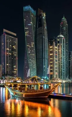 a boat on the water in a city at night at Cayan Tower Dubai Marina - By Home Of Choice in Dubai