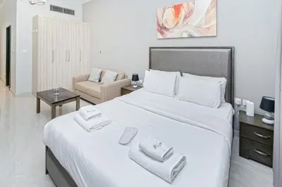 a white bedroom with a large bed with towels on it at Modern Studio with Canal View in Business Bay in Dubai