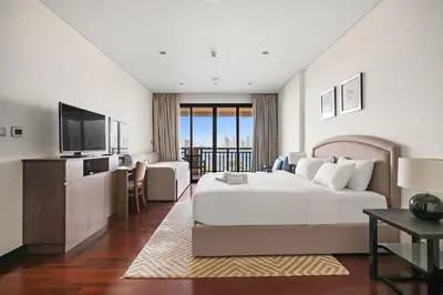 a hotel room with a bed and a television at Full Sea View 1 BR with Lagoon Pool & Beach Access in Dubai