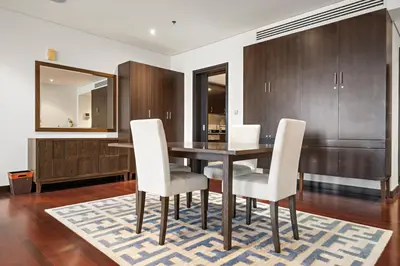 a dining room with a wooden table and white chairs at Full Sea View 1 BR with Lagoon Pool & Beach Access in Dubai