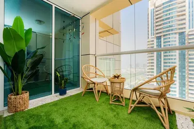 a balcony with two chairs and a table with grass at Dubai Marina - 1BHK Apartment in Dubai