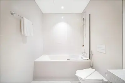 a white bathroom with a tub and a toilet at Silkhaus Sea & City View 1BDR in Exclusive Neighbourhood in Dubai