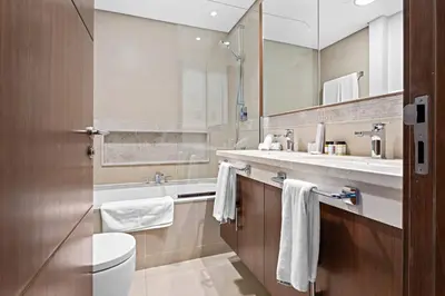 a bathroom with a sink and a toilet and a mirror at Downtown 3BR Sleeps 9 Balcony, Full Kitchen, Near Metro in Dubai