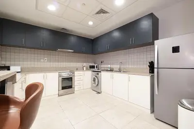 a kitchen with white cabinets and a refrigerator at Apartment KOYO in the heart of JBR Beach - 3BDR in Dubai