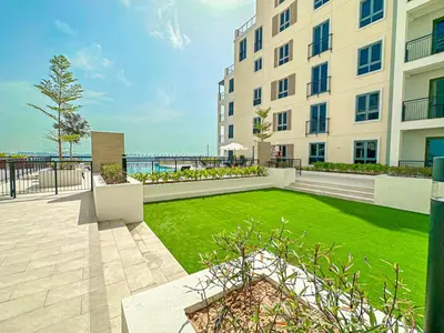 a large building with a green lawn in front of it at HiGuests - Luxurious Boho Beach 2BR Apartment in La Mer in Dubai
