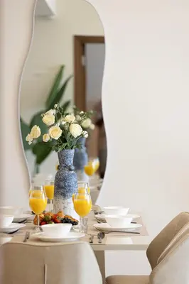 a table with a vase of flowers and orange juice at SmartStay at Zaya Hameni - Modern Luxury Apartments - Unique in JVC in Dubai