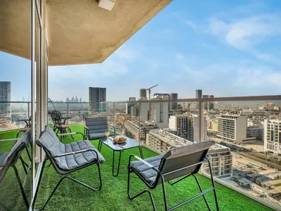 a balcony with chairs and a table and a view of a city at SmartStay at Zaya Hameni - Modern Luxury Apartments - Unique in JVC in Dubai