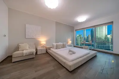 a white bedroom with a large bed and a window at Top-Floor Luxury 2BR with Stunning Marina View in Dubai