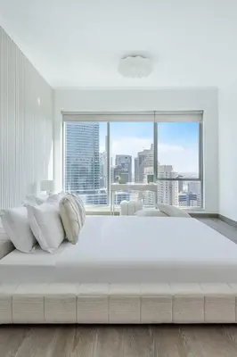 a large white bed in a room with a large window at Top-Floor Luxury 2BR with Stunning Marina View in Dubai