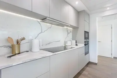 a white kitchen with white cabinets and a counter top at Top-Floor Luxury 2BR with Stunning Marina View in Dubai