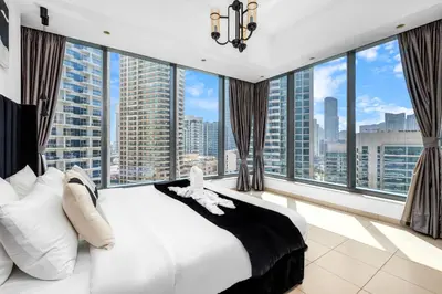 a bedroom with a large bed and large windows at Panoramic 1BR Stunning Marina Views Near JBR Beach by Maxx Value Homes in Dubai