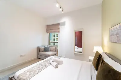 a white bedroom with a bed and a chair at Prime Spacious 5 plus 1 BR Apt on JBR Beach near Metro ,Walk to The Mall, Dining & Entertainment - By Sunkissed Holiday Homes in Dubai