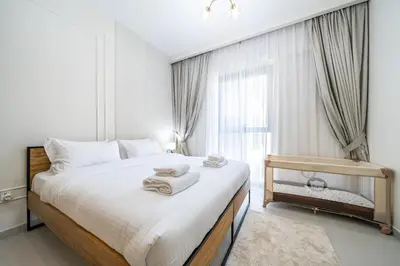 a bedroom with a large bed with towels on it at SettlerHomes - Marvelous Lagoon Stay With Pool View in Dubai