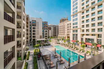 an apartment balcony with a swimming pool and buildings at SettlerHomes - Marvelous Lagoon Stay With Pool View in Dubai