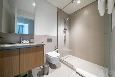 a bathroom with a toilet and a glass shower at SettlerHomes - Marvelous Lagoon Stay With Pool View in Dubai