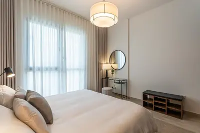 a white bedroom with a large bed and a mirror at Modern 1BDR Apartment I Madinat Jumeirah Living I Asayel 3 in Dubai