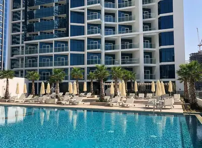 a pool with chairs and umbrellas in front of a building at Studio Apartment in DAMAC Maison Prive Business Bay - High Floor in Dubai