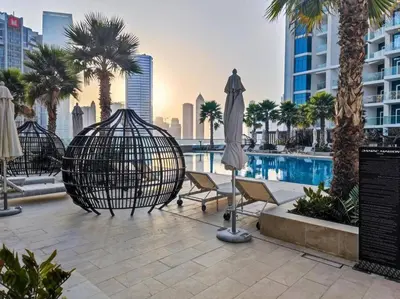 a pool with chairs and an umbrella and palm trees at Studio Apartment in DAMAC Maison Prive Business Bay - High Floor in Dubai