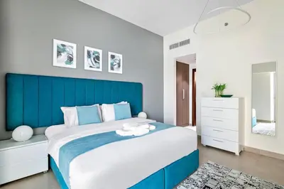 a bedroom with a large bed with a blue headboard at Stylish 1 BR in Al Furjan in Dubai