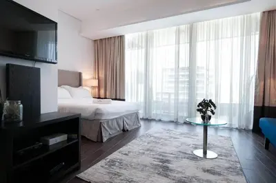 a hotel room with a bed and a table with flowers at Cozy Studio in Sports City in Dubai