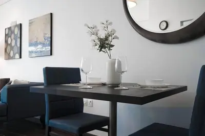 a dining room table with two wine glasses and a mirror at Cozy Studio in Sports City in Dubai