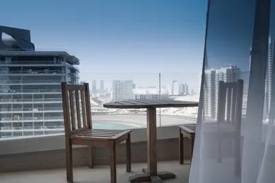 a table and chairs on a balcony with a view of a city at Cozy Studio in Sports City in Dubai