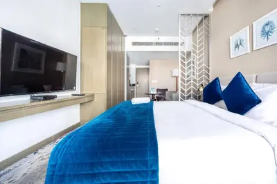 a hotel room with a large bed and a flat screen tv at Studio Apartment in DAMAC Maison Prive Businessbay - Dubai Canal View in Dubai