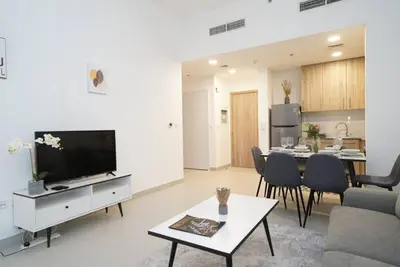 a living room with a television and a dining room at Spacious 1 BR in Peaceful Community in Dubai