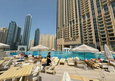 a swimming pool with people sitting in chairs and umbrellas at Dubai Marina Residences, Studio with Balcony Connected to Marina Mall in Dubai