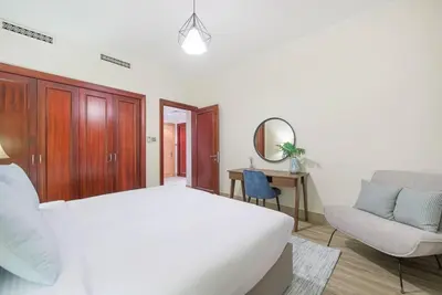 a white bedroom with a white bed and a chair at Stylish 2BR with Balcony Near Dubai Mall and Burj Khalifa in Dubai