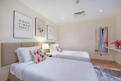 two beds in a room with white walls at Stylish 2BR with Balcony Near Dubai Mall and Burj Khalifa in Dubai