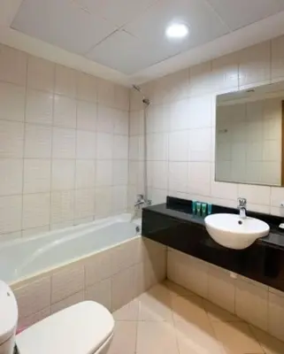 a bathroom with a sink and a tub and a toilet at Cozy Furnished Studio in Dubai