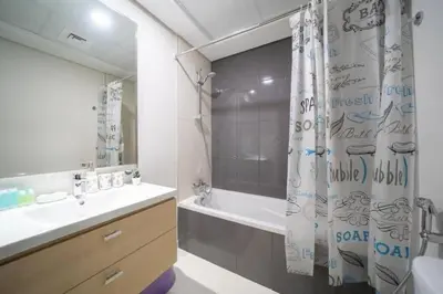 a bathroom with a tub and a shower curtain at Furnished Cozy Studio in Dubai
